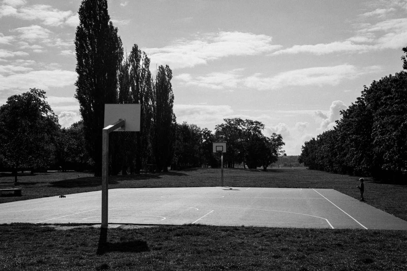 A child operates a remote-controlled four-wheel drive on a basketball court inside Tempelhofer Feld, the former airport terminal visible in the distance.