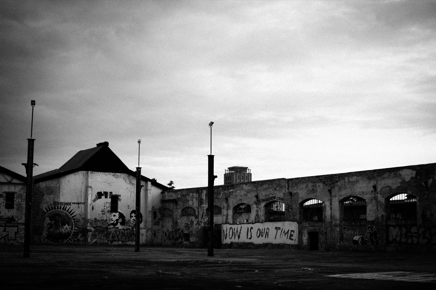Graffiti reading NOW IS OUR TIME painted on the side of a maintenance hall at the RAW-Gel&auml;nde in Friedrichshain.