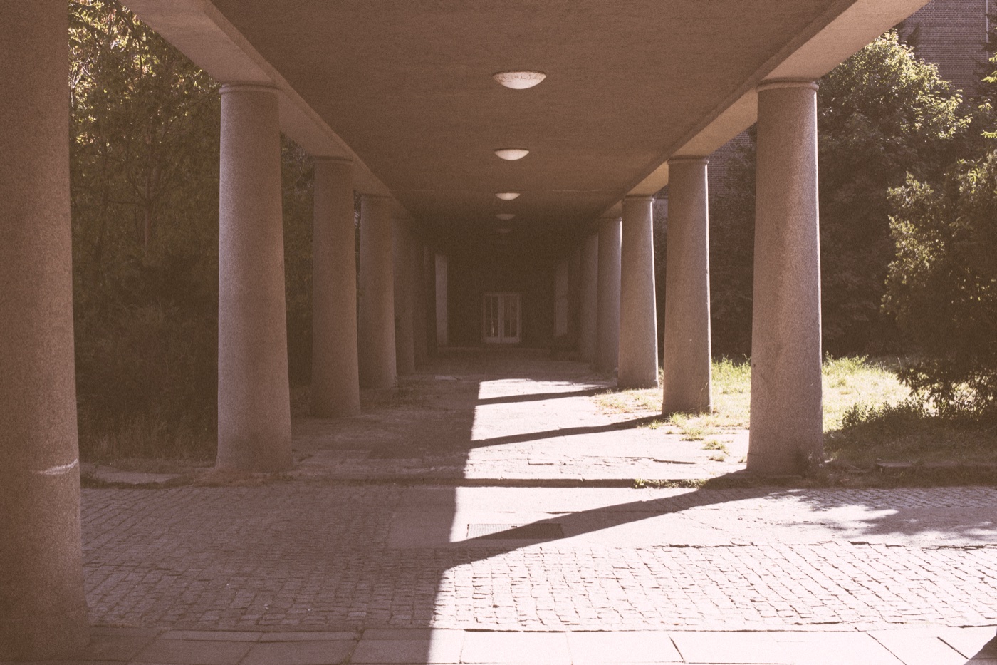 The exterior cloister at Funkhaus Berlin &mdash; columns receding in clean geometry on one side, deep shadow on the other.