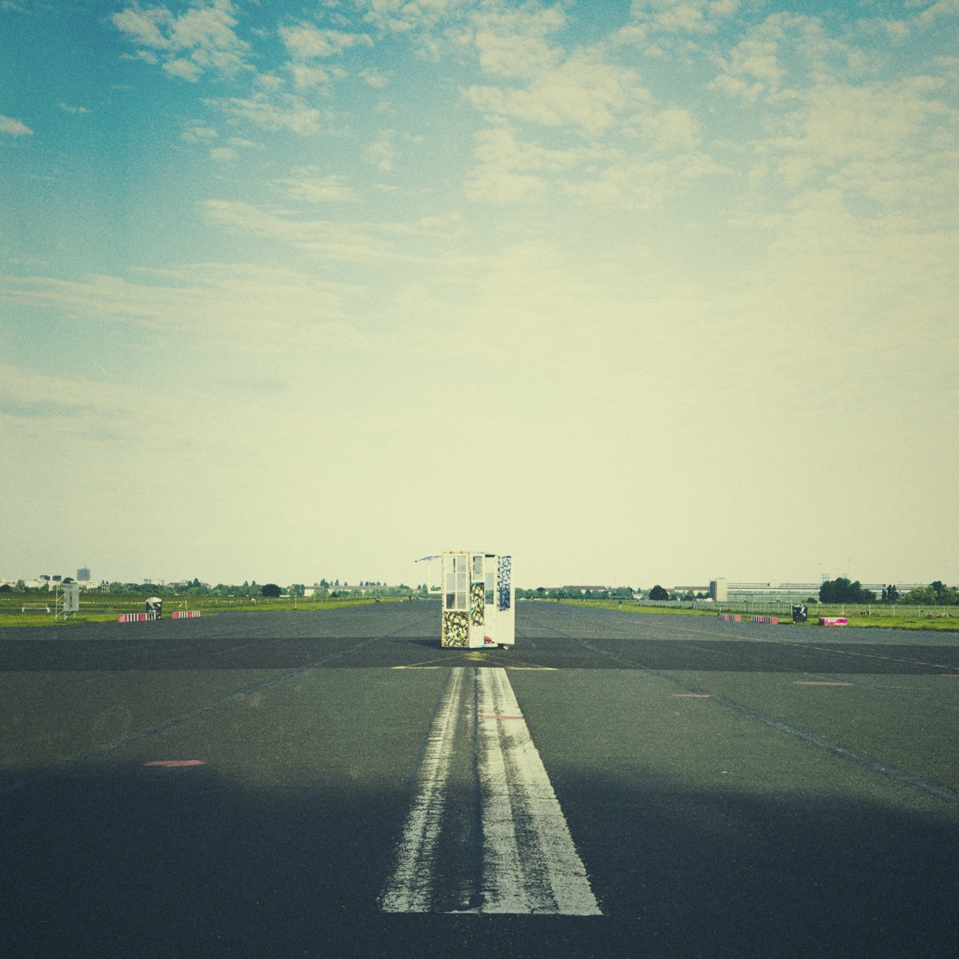 A red phone booth &mdash; the Teleporter Phone Booth installation &mdash; stands alone at the end of one of Tempelhof's runway markings.