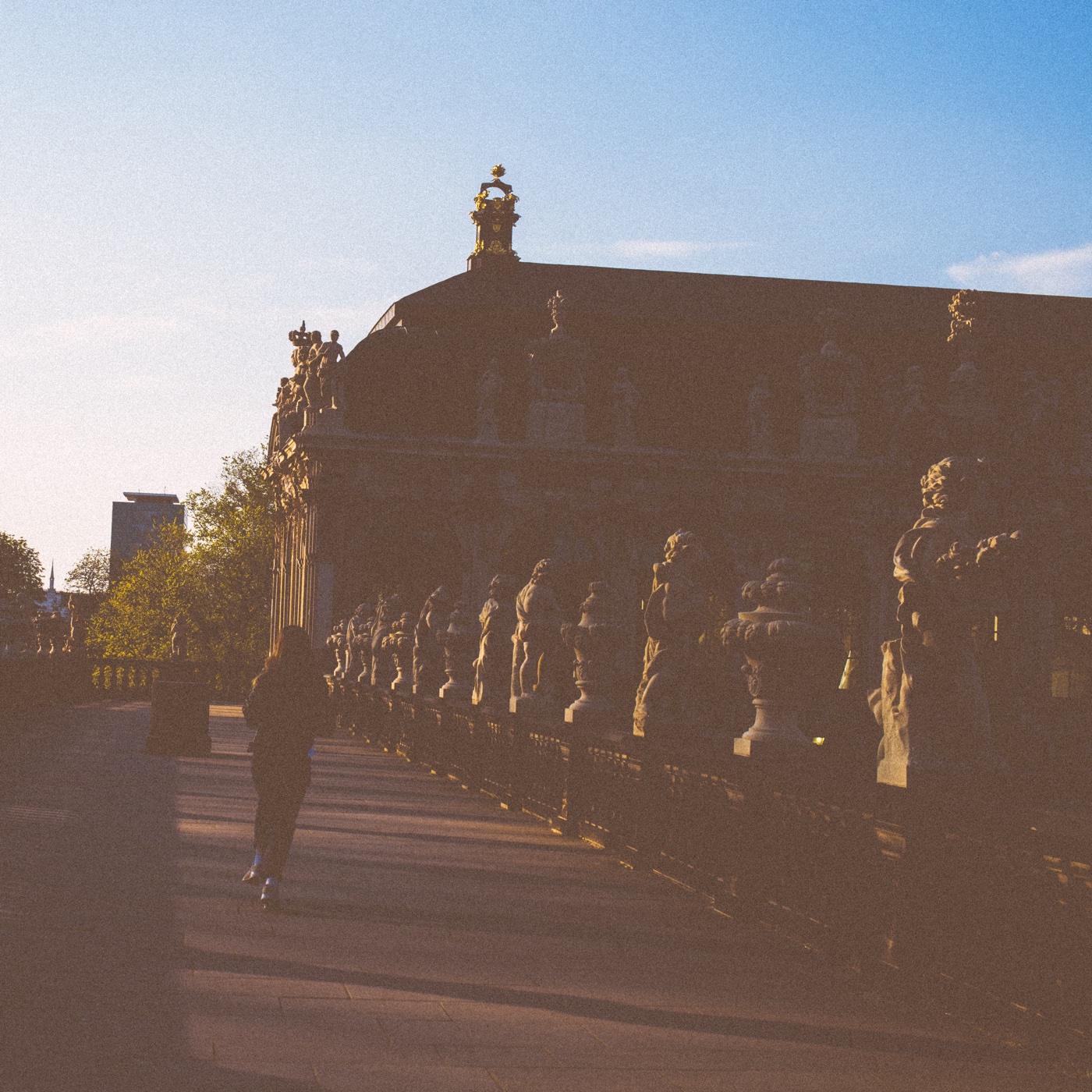 A lone runner moves away from the camera through central Dresden, the gothic-reconstructed skyline rising in the background.